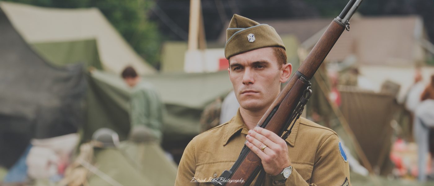A soldier standing at attention with an M1 Garand rifle, his posture straight and eyes forward. The scene highlights the soldier's discipline and readiness, embodying the professionalism and pride of military service.